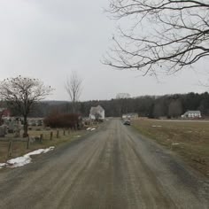 an empty road in the middle of a rural area with houses and trees on either side