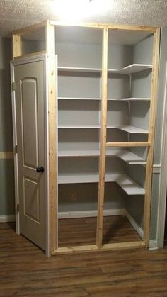 an empty closet with shelves and doors in the corner, next to a door that is open