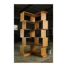 a tall wooden shelf sitting in the middle of a room next to a potted plant