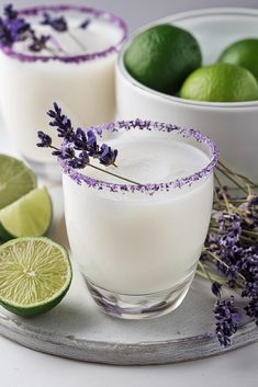 two margaritas with lavender and lime garnish sit on a tray