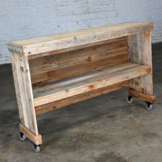 a wooden bench sitting on wheels in front of a brick wall