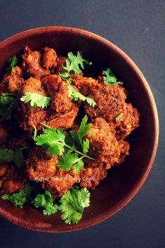 a bowl filled with meat and cilantro on top of a black tablecloth