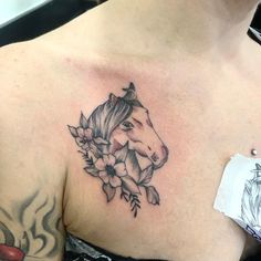 a woman's chest with a horse and flowers tattoo on her left side shoulder