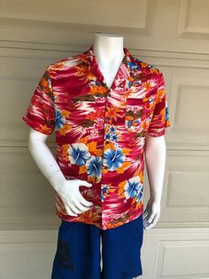 Vintage gorgeous Hawaiian shirt in a hot pink, orange and blue hibiscus and cityscape print.  Excellent vintage condition with no issues. label:  Mr. Jan fabric:  polyester sateen weave size:  labeled size is large.  Modern size may be smaller.  Please check measurements for an accurate fit.  Questions are welcome! Shirt was measured flat across the front side. underarm to underarm 23 length 28 1/2 shoulder 19 1/2 Vacation Multicolor Print Shirt With All Over Print, Multicolor Short Sleeve Shirt With Vibrant Print, Multicolor Vibrant Print Short Sleeve Shirt, Hawaiian Printed Relaxed Fit Shirt, Casual Multicolor Shirt With Tropical Print, Vibrant Multicolor Print Short Sleeve Shirt, Orange Short Sleeve Shirt For Vacation, Vibrant Red Short Sleeve Top, Pink Collared Hawaiian Shirt For Beach