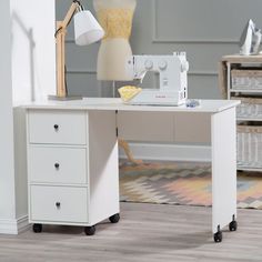 a sewing machine sitting on top of a white table next to a lamp and dresser