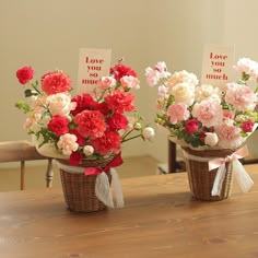 two baskets filled with flowers sitting on top of a wooden table next to each other