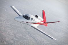 a small white and red plane flying in the sky