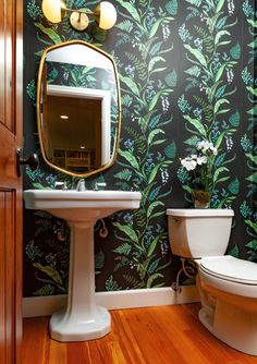 a bathroom with a toilet, sink and mirror on the wall next to each other