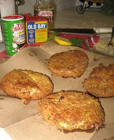 four crab cakes sitting on top of a cardboard box next to other food and condiments