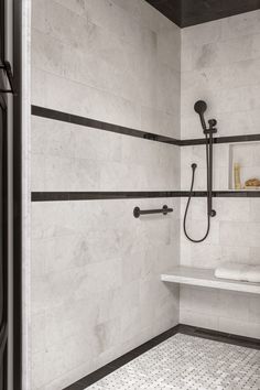 a white tiled bathroom with black trim and shower head, shelves on either side of the tub