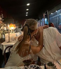 a man and woman sitting at a table with wine glasses in front of their faces