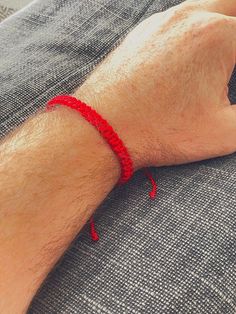 a man wearing a red string bracelet on his arm