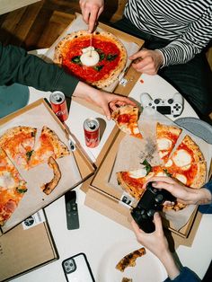 several people eating pizza at a table with drinks and cell phones on the table in front of them