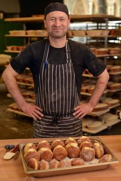 a man standing in front of a tray of doughnuts