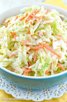 a bowl filled with coleslaw and carrots on top of a doily