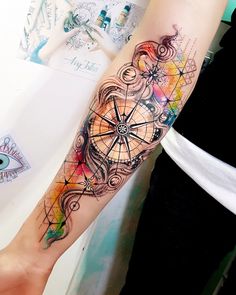 a woman's arm with a compass tattoo on it and an eye in the background