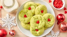 green cookies with red hearts are on a plate next to christmas decorations and other items