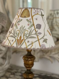 a table lamp sitting on top of a wooden table next to a mirror and statue