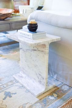 a white marble table with a black vase sitting on it's top next to a couch