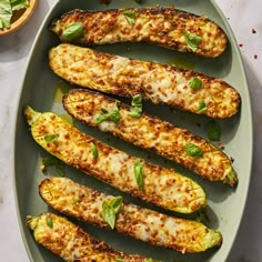 grilled zucchini with basil and cheese on a plate next to a bowl