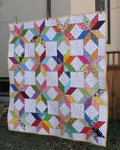 a colorful quilt is hanging on the side of a building in front of a house