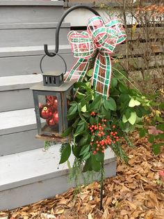 a lantern with a bow on it is sitting in front of some leaves and berries