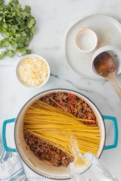 pasta being cooked in a pot with parmesan cheese and sauce on the side