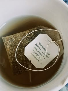 a tea bag in a white cup filled with green tea and some kind of label