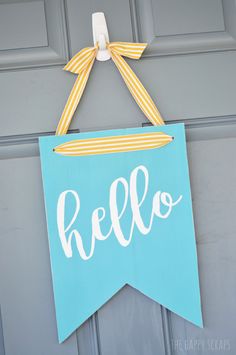 a door hanger with the word hello painted on it and a bow hanging from it