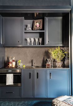 a kitchen with blue cabinets and silver counter tops is pictured in this image, there are vases on the shelves