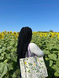 a woman standing in the middle of a sunflower field with her back to the camera