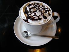 a cup of hot chocolate with marshmallows in it on a saucer