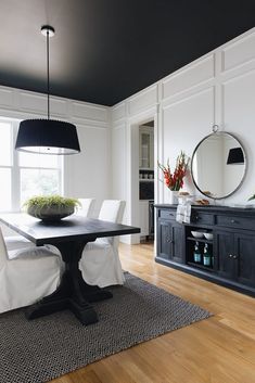 a black and white dining room with wood flooring, large round mirror on the wall