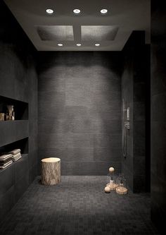 a modern bathroom with black tile and white fixtures, including a shower head in the corner