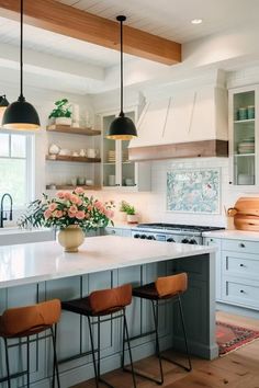 a kitchen island with three stools in front of it and flowers on the counter