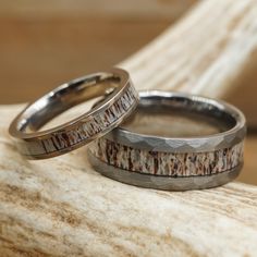 two wedding rings sitting on top of a piece of driftwood next to each other