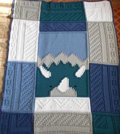 a blue and white blanket with an animal on it's side, sitting on top of a bed