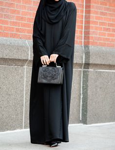 Be stylish and sophisticated with our lovely Sanijah Abaya. The Sanijah Abaya is meticulously hand-beaded with every single crystal tastefully adorned over the back and front of the abaya. Crafted in luxurious, lightweight crepe, the Sanijah Abaya offers a comfortable fit without compromising style. The Classic Black s Black Abaya Designs Simple, Hijab Closet, Abaya Ideas, Hijab Gown, Simple Abaya, Abaya Collection