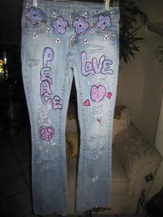 This is a lovely pair of upcycled, painted jeans. which has been  distress i've  added cute little painted flowers, front and back . also i've distress them in different areas. also added the word, peace and love. i've also added a heart and a peace sign, and other little detailsthe brand is american eagle the fabric is 99% cotton and 1% spandex also they are a size 2 reg  stretchto you  ladies out there , this would be a nice pair of jeans, added to your collection!as always thank you!!  for stopping by. Casual Embellished Cotton Jeans, Jeans Embellished, Peace Sign Art, Lace Jeans, Bohemian Girls, Hippie Peace, Painted Jeans, Embellished Top, Painted Flowers