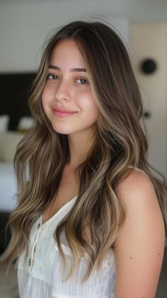 Smiling woman with long wavy hair and a white top indoors. Brunette Going Blonde, Brunette With Caramel Highlights, Golden Brown Highlights, Dimensional Highlights, Partial Balayage, Trendy Fall Hair Color, Sun Kissed Highlights, Dimensional Brunette, Coffee Caramel