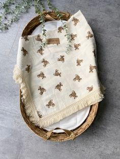 a wicker basket with a white and brown blanket on it next to a plant