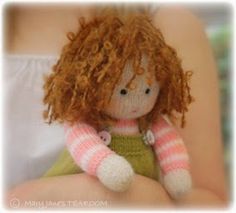 a little red haired doll sitting on top of a woman's stomach