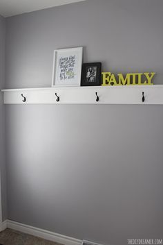 there is a shelf with hooks on it and two pictures hanging from the wall above