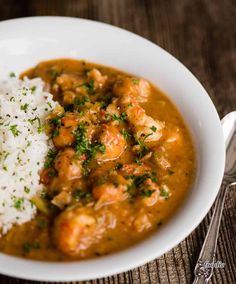 a white bowl filled with rice and some kind of meat stew next to a fork