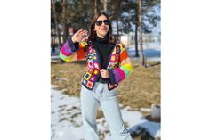 a woman standing in the snow with her arms out and wearing sunglasses on top of her head