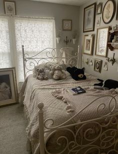 a bedroom with pictures on the wall and stuffed animals on the bed in front of it