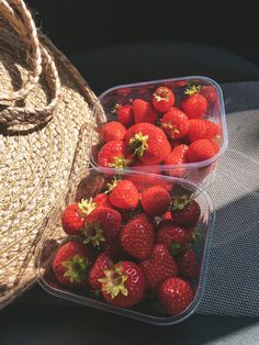 two plastic containers filled with strawberries on top of a seat