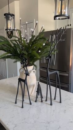 a white vase filled with green plants on top of a kitchen counter next to an oven