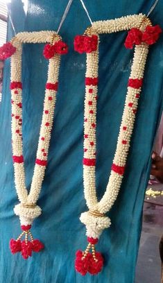 two white and red garlands are hanging on a blue cloth covered stand with flowers