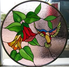 a close up of a stained glass window with a bird and flower design on it